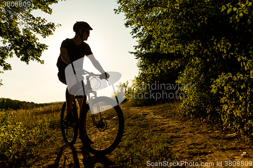 Image of Man Cyclist with bike on sunset