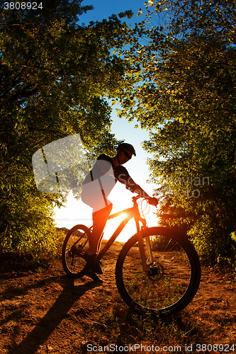 Image of Man Cyclist with bike on sunset