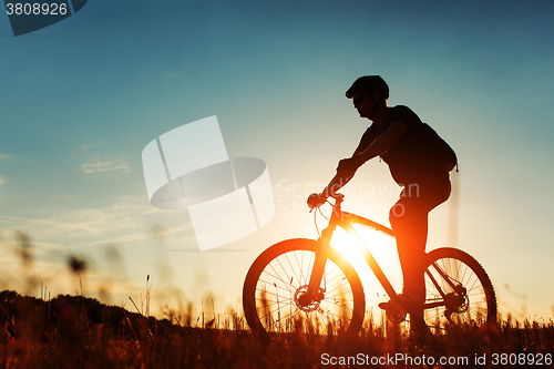 Image of Man Cyclist with bike on sunset