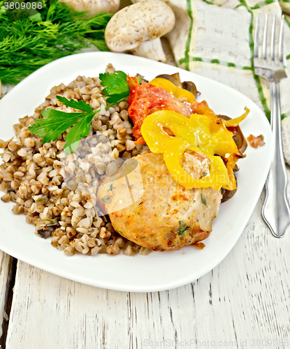 Image of Cutlets of turkey with buckwheat and vegetables in plate on boar