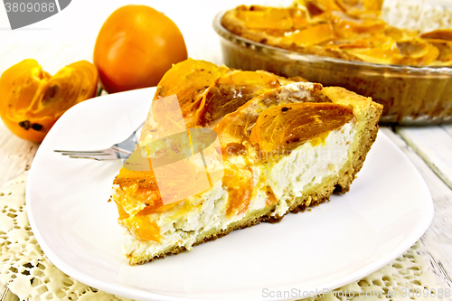 Image of Pie with curd and persimmons in white plate on napkin silicone