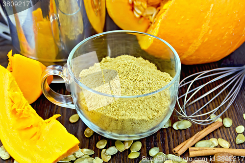 Image of Flour pumpkin in glass cup with seeds and sieve on board