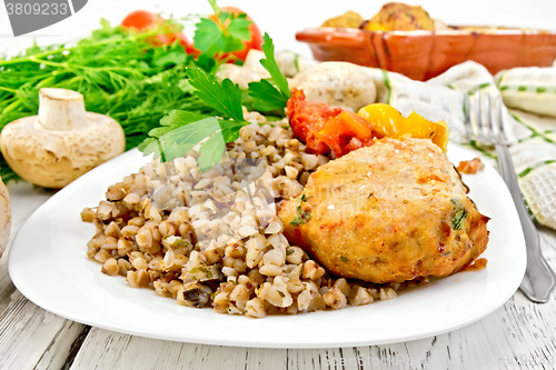 Image of Cutlets of turkey with buckwheat and mushrooms in plate on board