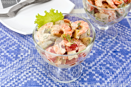 Image of Salad with shrimp and tomatoes in glass on blue tablecloth