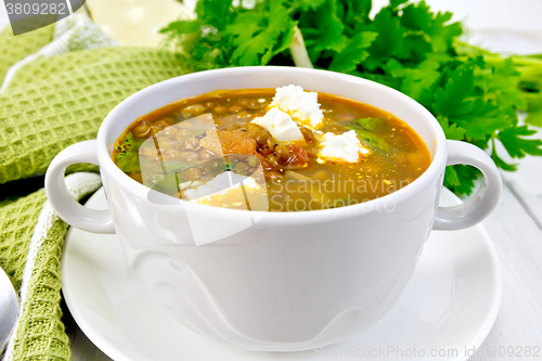 Image of Soup lentil with spinach and cheese in white bowl on board