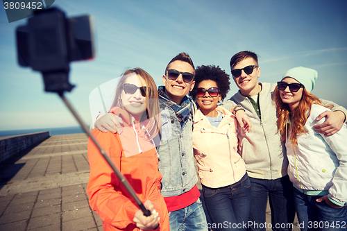 Image of smiling friends taking selfie with smartphone