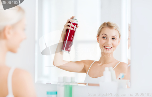 Image of woman with hairspray styling her hair at bathroom