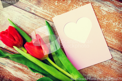 Image of close up of tulips and greeting card with heart