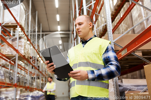 Image of man with clipboard in safety vest at warehouse