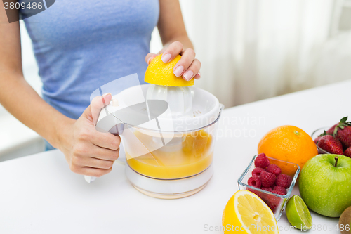 Image of close up of woman squeezing fruit juice at home