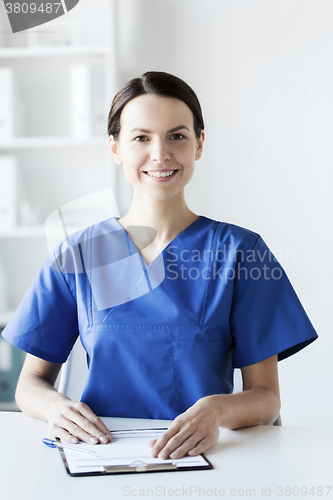 Image of happy doctor or nurse with clipboard at hospital