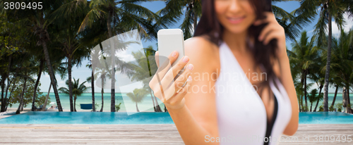 Image of young woman taking selfie with smartphone on beach