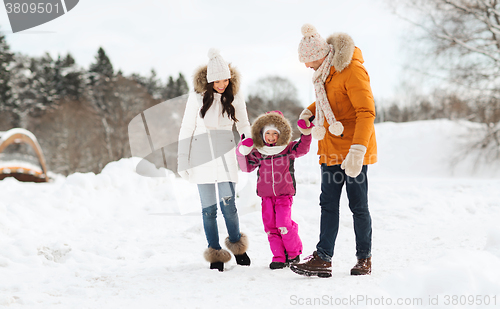 Image of happy family in winter clothes walking outdoors