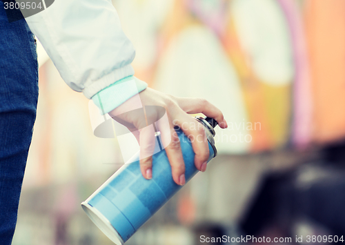 Image of close up of hand holding spray paint and graffiti