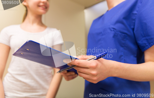 Image of close up of nurse with clipboard and pen with girl