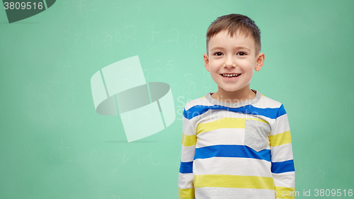 Image of happy smiling little boy over green school board