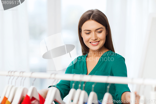 Image of happy woman choosing clothes at home wardrobe