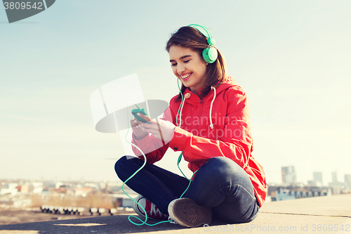 Image of happy young woman with smartphone and headphones