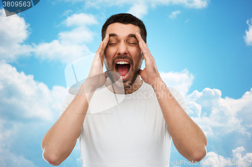 Image of crazy shouting man in t-shirt over blue sky