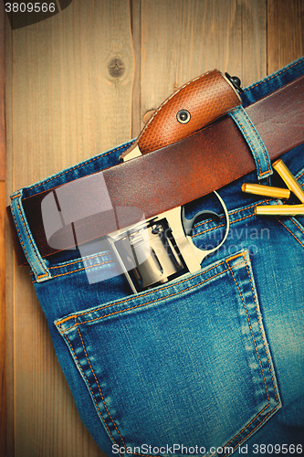 Image of old silver revolver and vintage blue jeans