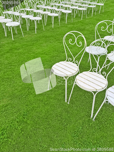 Image of Empty white chairs on the green lawn