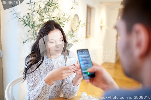 Image of couple with smartphones at cafe