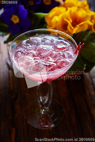 Image of cosmopolitan cocktail garnished with ice on wooden table 