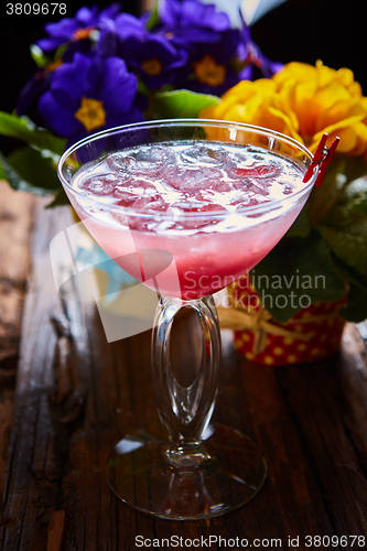 Image of cosmopolitan cocktail garnished with ice on wooden table 