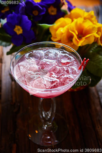 Image of cosmopolitan cocktail garnished with ice on wooden table 