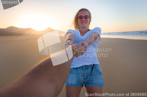 Image of Romantic couple, holding hands, having fun on beach.