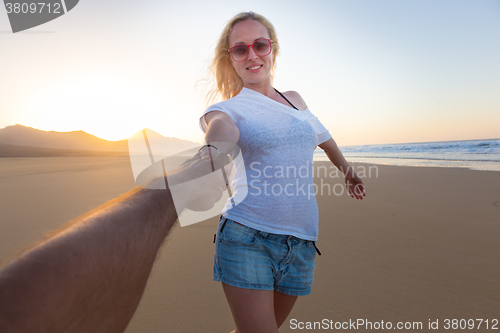 Image of Romantic couple, holding hands, having fun on beach.