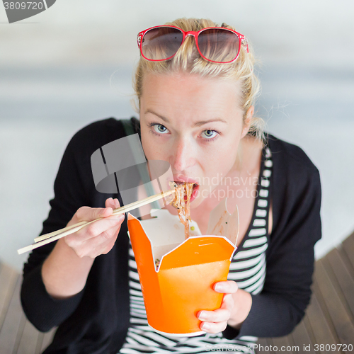 Image of Woman eating Chinese take-away noodels.
