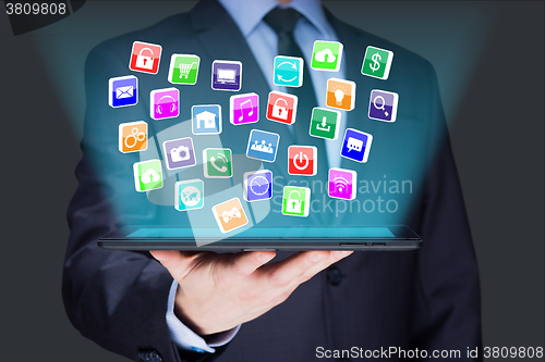 Image of Businessman holding a tablet pc with mobile applications icons on virtual screen . Internet and business concept.