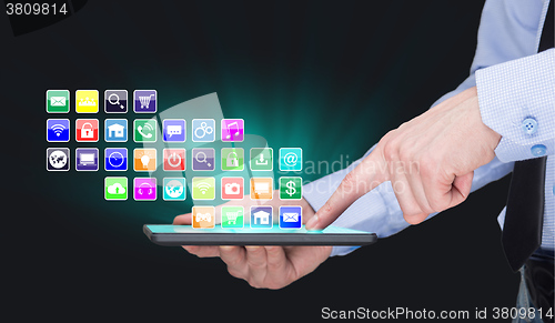 Image of Businessman holding a tablet pc with mobile applications icons on virtual screen . Internet and business concept.
