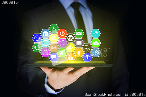 Image of Businessman holding a tablet pc with mobile applications icons on virtual screen . Internet and business concept.