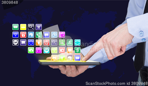 Image of Businessman holding a tablet pc with mobile applications icons on virtual screen . Internet and business concept. World map