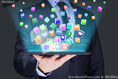 Image of Businessman holding a tablet pc with mobile applications icons on virtual screen . Internet and business concept.