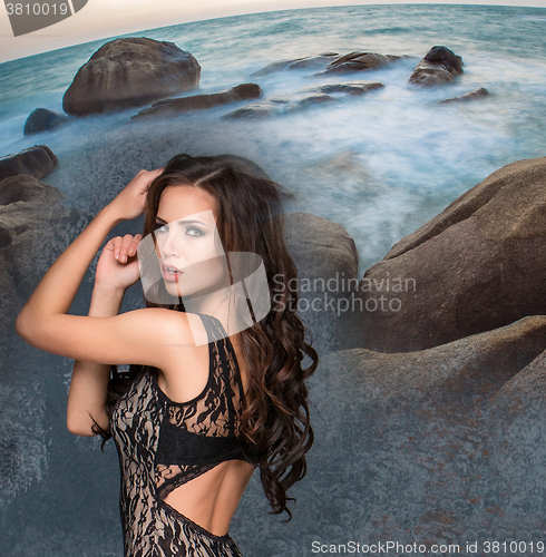 Image of Beautiful young brunette woman against rocky shore or beach 