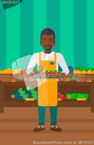 Image of Supermarket worker with box full of apples.