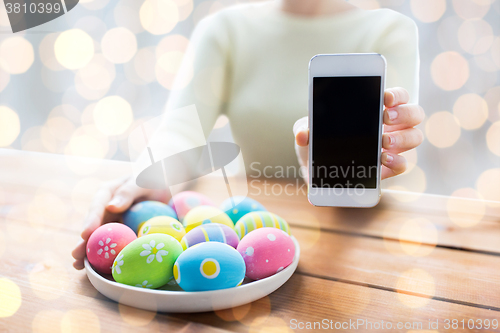 Image of close up of hands with easter eggs and smartphone