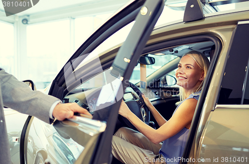 Image of happy woman with car dealer in auto show or salon