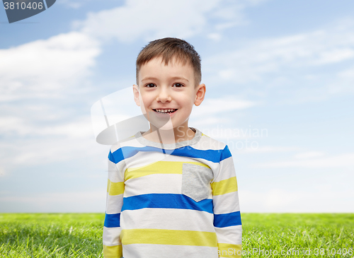 Image of smiling little boy over blue sky and green field