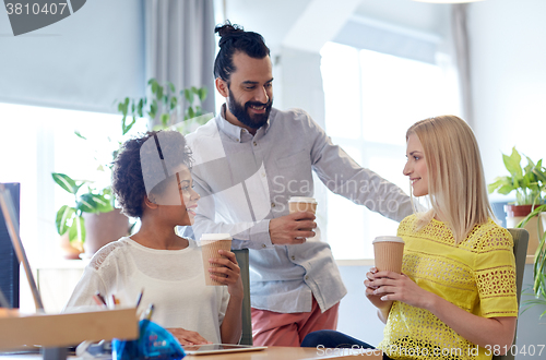 Image of happy creative team drinking coffee in office