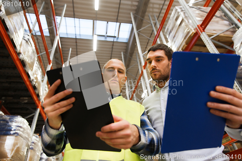 Image of worker and businessmen with clipboard at warehouse