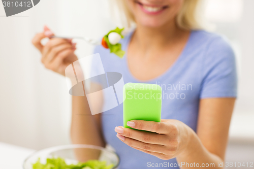 Image of close up of woman with smartphone eating salad