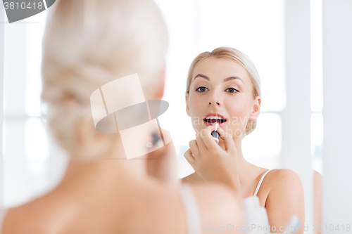 Image of woman with lipstick applying make up at bathroom