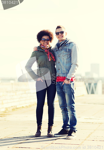 Image of happy teenage friends in shades hugging outdoors