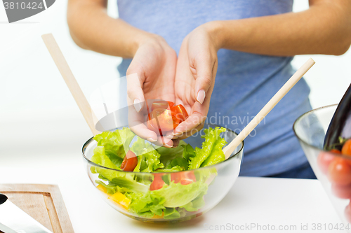 Image of close up of woman cooking vegetable salad at home