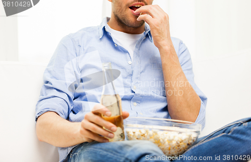 Image of close up of man with popcorn and beer at home