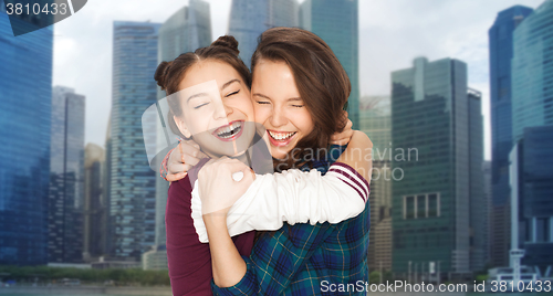 Image of happy smiling teenage girls hugging over city